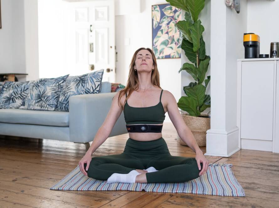 a woman sitting on a yoga mat in a living room
